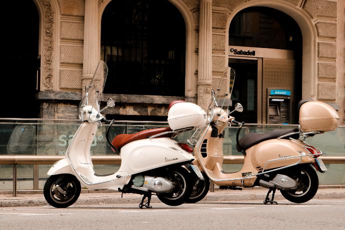 red and white motor scooter parked beside brown concrete building during daytime